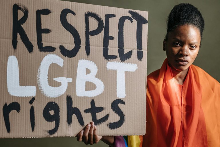Woman holding a sign advocating for LGBT rights, highlighting social justice.