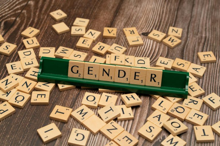 Wooden letter tiles spelling 'gender' on a game board, highlighting gender concepts.